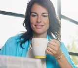  Kvinde drikker kaffe og læser avis.