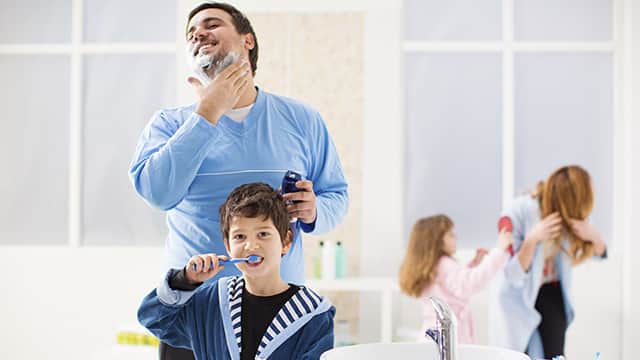 dreng børster tænder, mens hans far barberer sig